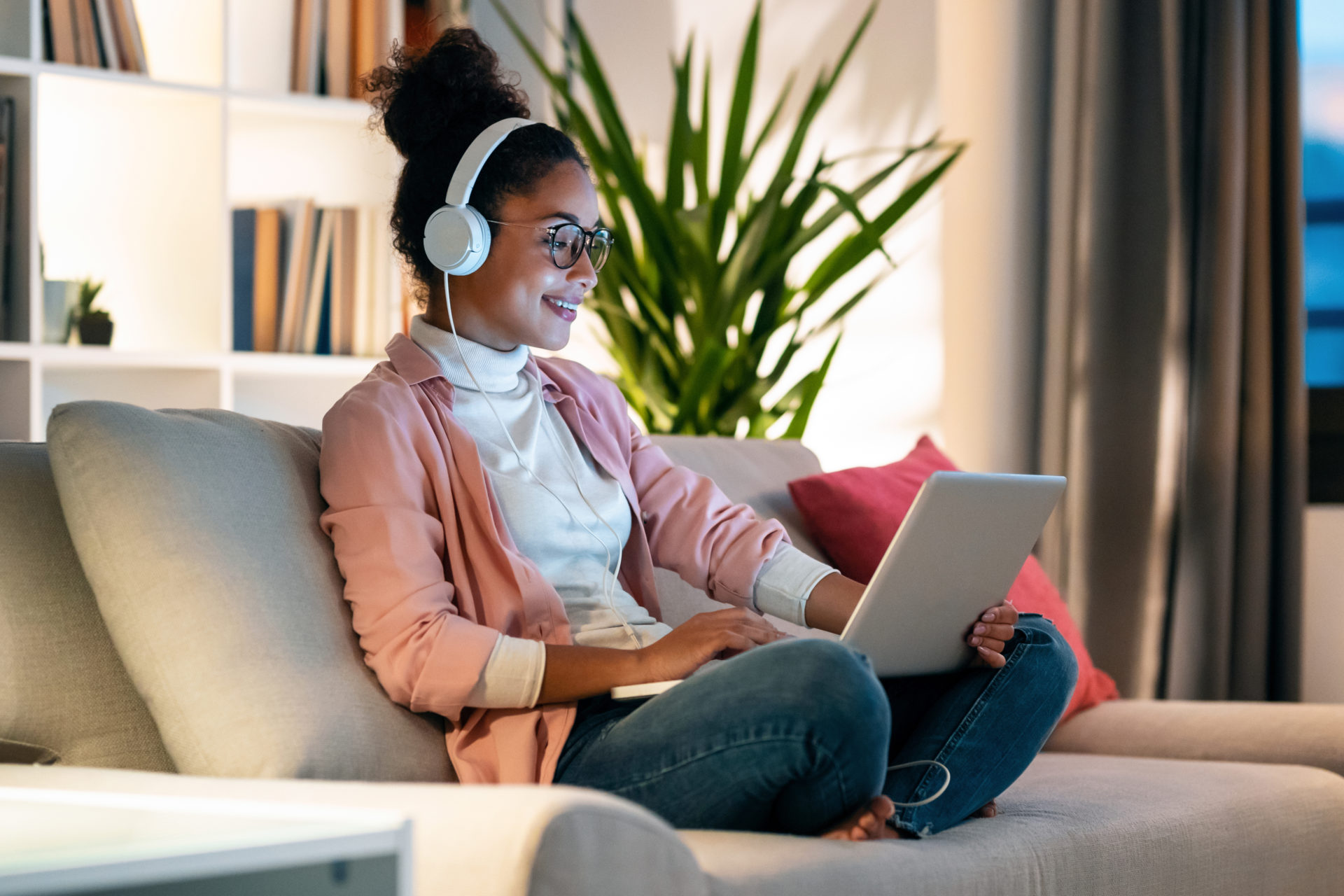 woman sat listening to music using headphones and electrical device