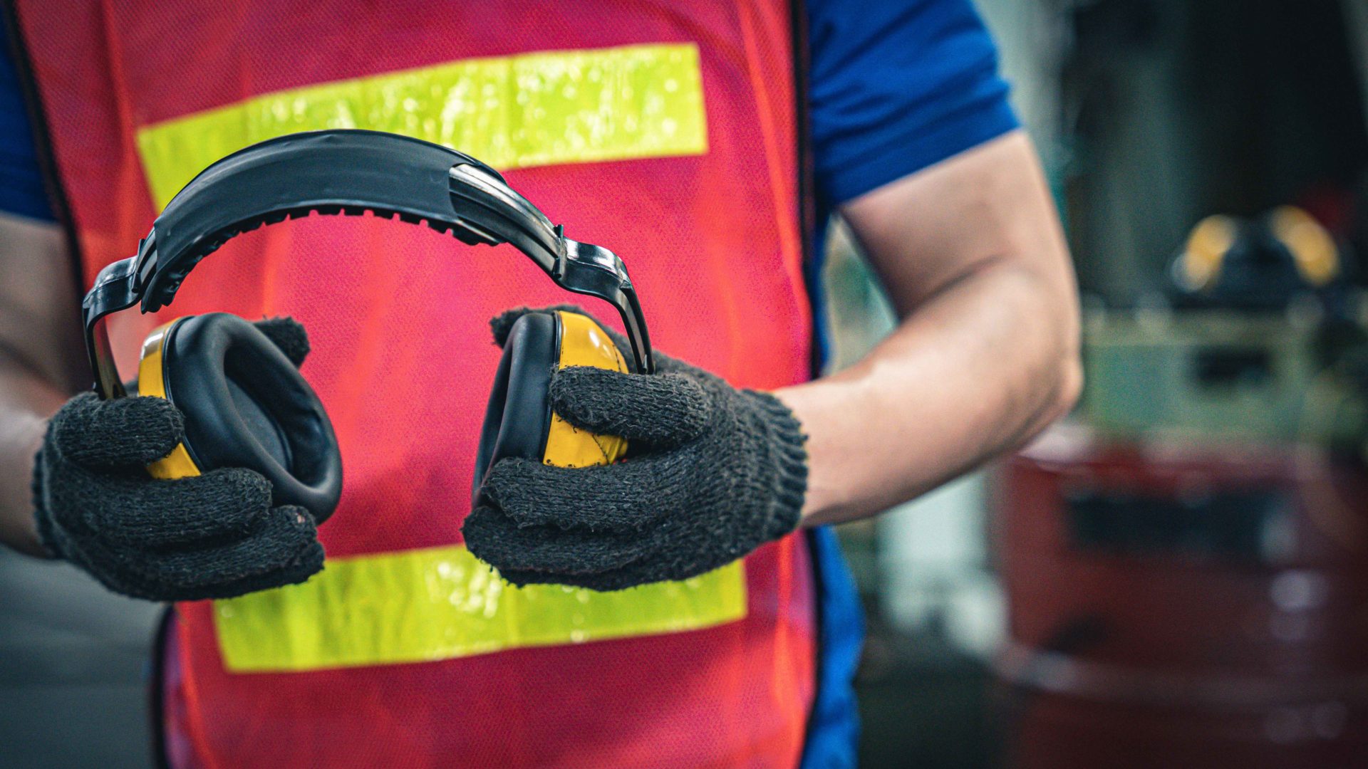 male worker holding headphones to protect hearing in loud enviroment